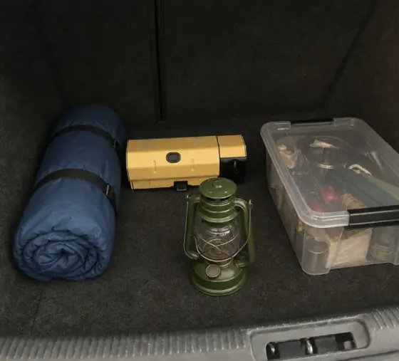 Qinux GoFlamex packed in a car trunk with a sleeping bag and lantern